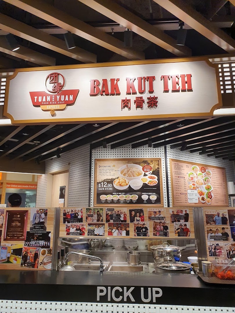 A food stall named Tuan Yuan Bak Kut Teh with a pick-up counter and menu boards.