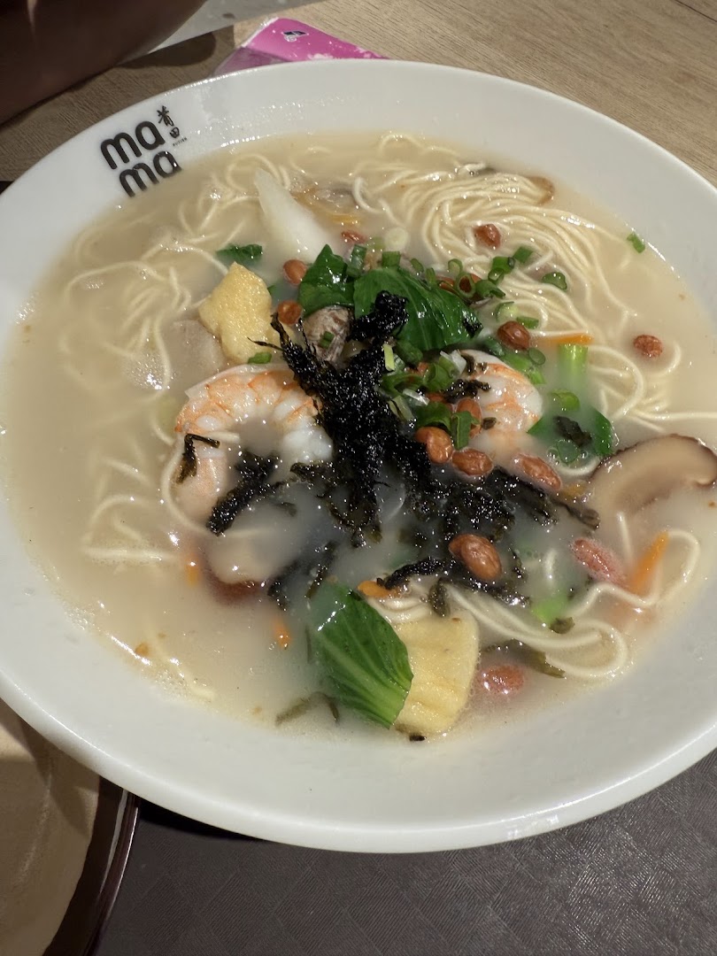 A close-up of a delicious bowl of seafood noodles with prawns, vegetables, and peanuts.