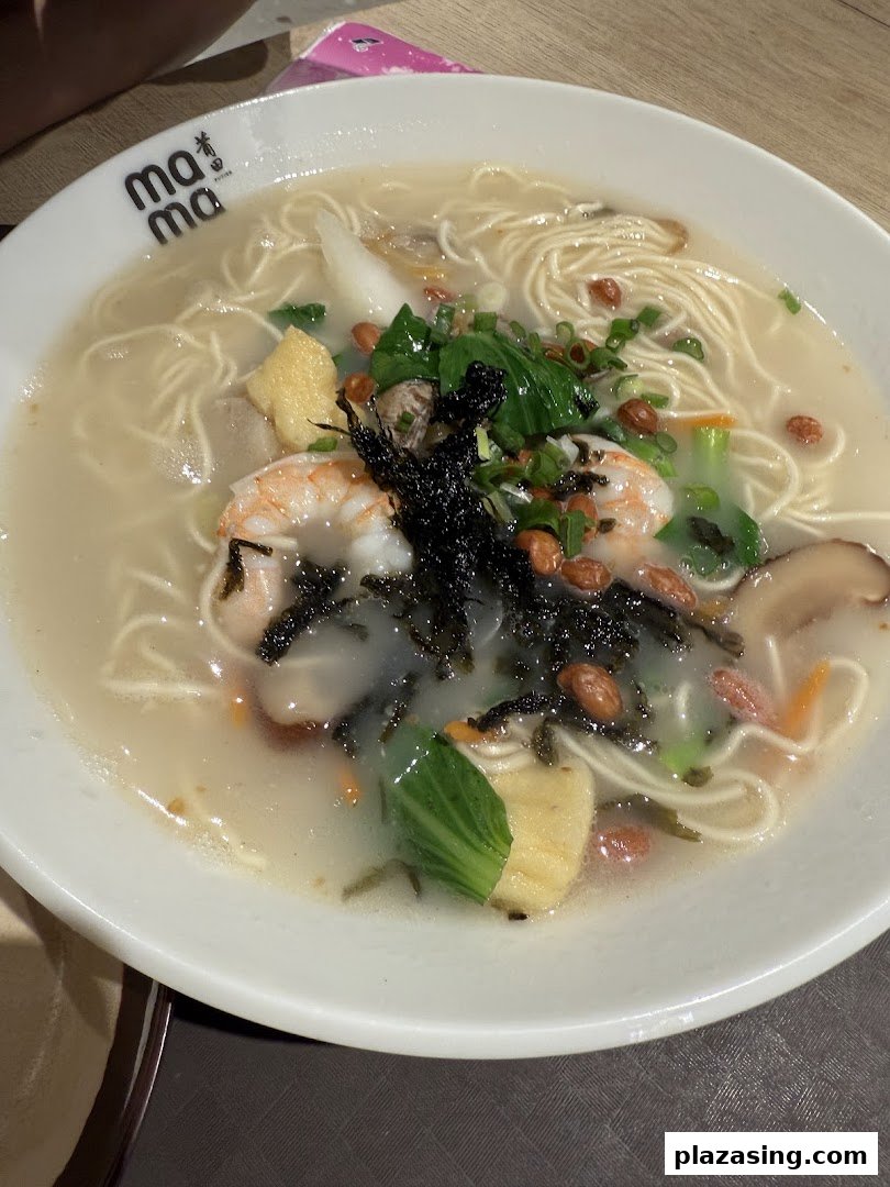 A close-up of a delicious bowl of seafood noodles with prawns, vegetables, and peanuts.