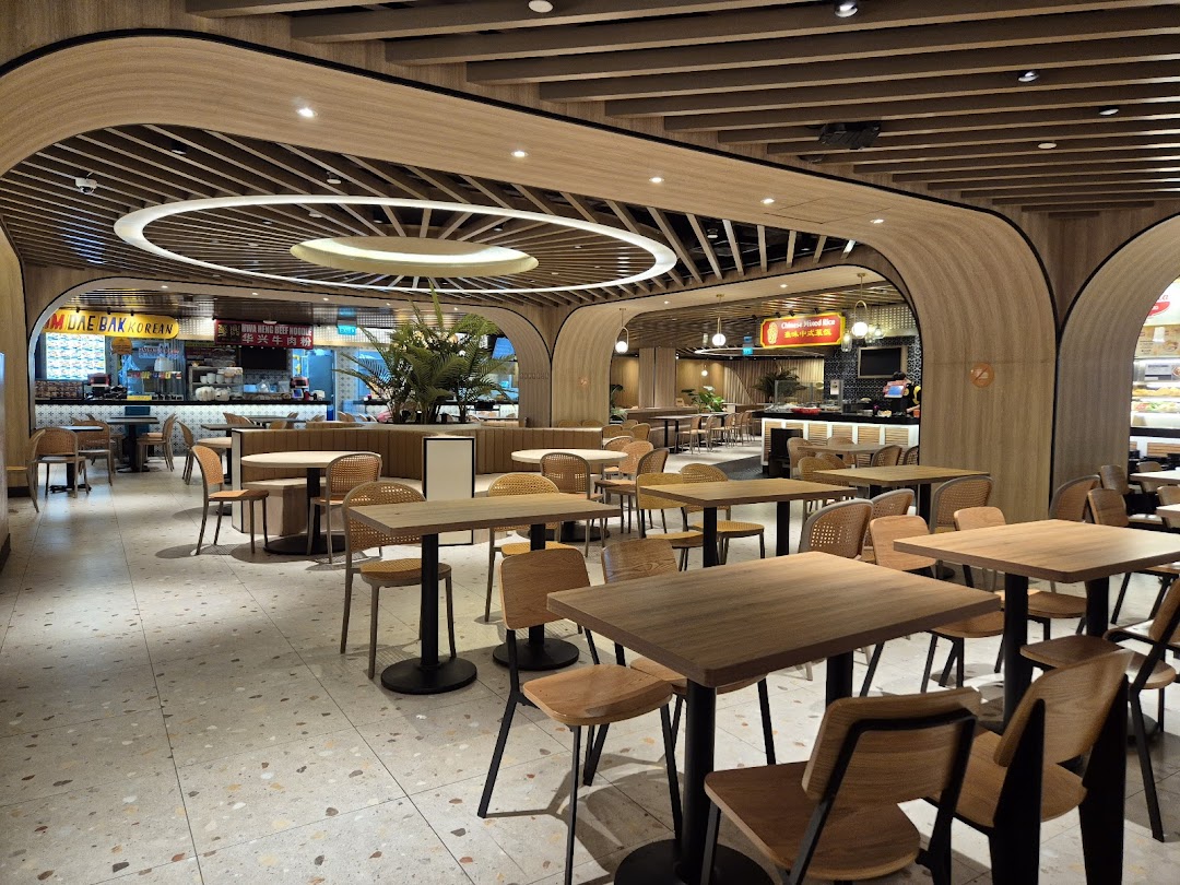 A spacious and modern food hall interior with numerous dining tables and various food stalls.
