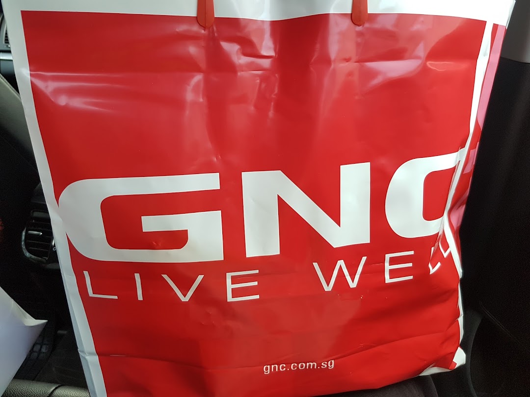 A vibrant red GNC shopping bag featuring the 'LIVE WELL' slogan and brand website.