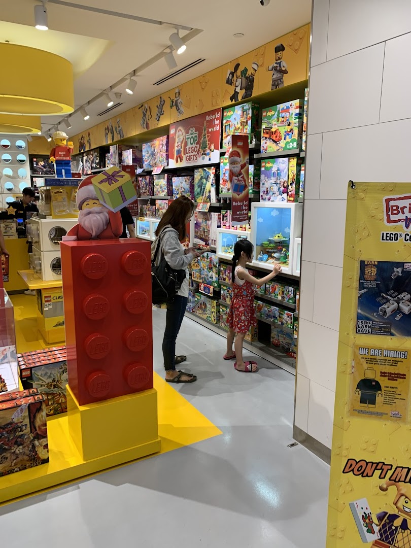 Customers browse colorful LEGO sets and displays inside the brightly lit store.