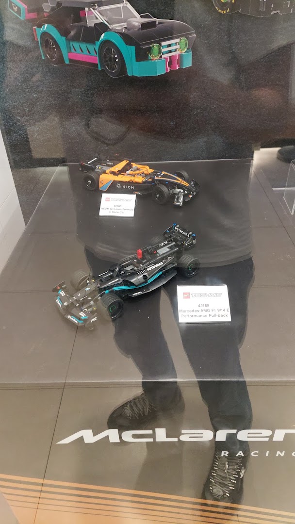 Close-up of LEGO Technic racing car models on display, including Mercedes-AMG F1 and McLaren.