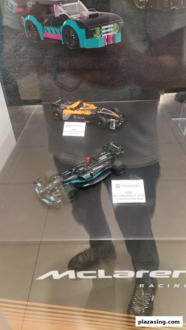 Close-up of LEGO Technic racing car models on display, including Mercedes-AMG F1 and McLaren.