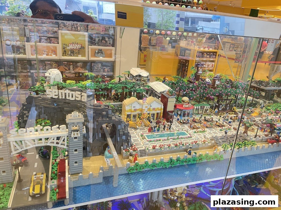 A detailed LEGO model of Sentosa Island, featuring landmarks and vibrant scenes, displayed in a glass case.