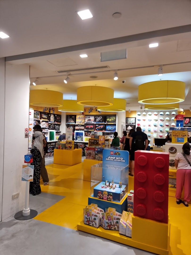 Vibrant interior of a LEGO Certified Store with yellow floors, product displays, and customers browsing.