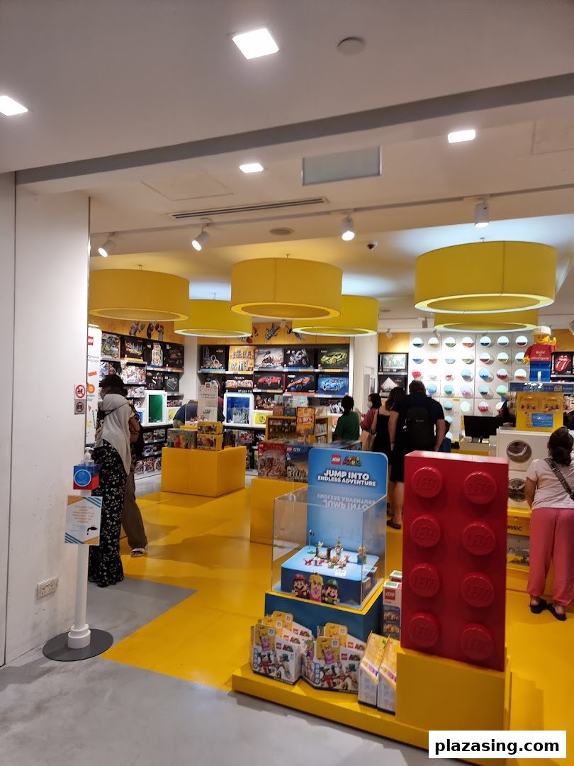 Vibrant interior of a LEGO Certified Store with yellow floors, product displays, and customers browsing.