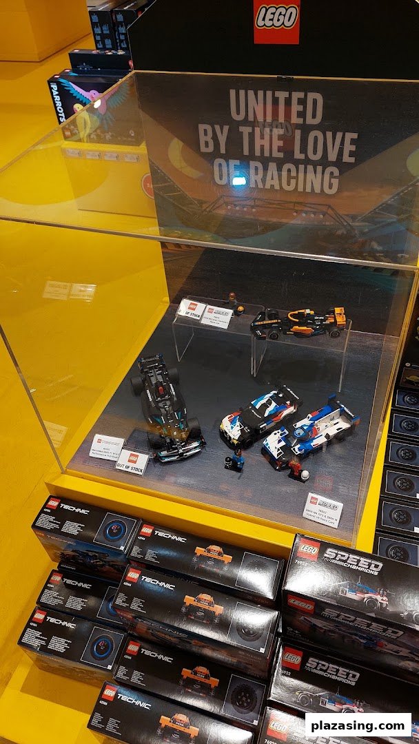 A vibrant LEGO display features racing car models and Technic sets, showcasing the 'United by the Love of Racing' theme.