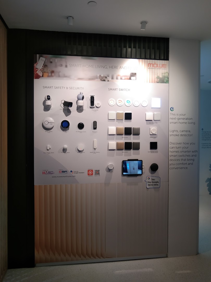 A wall display showcasing MOWE smart home devices, including security systems and smart switches.