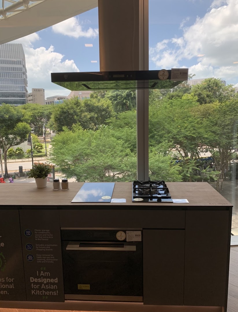 A modern kitchen display featuring an oven, hob, and hood with a city view.
