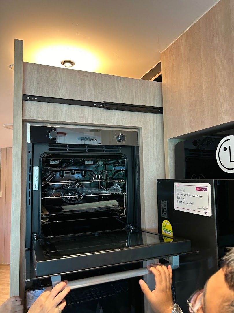 A modern kitchen display featuring an open oven and an LG smart refrigerator.