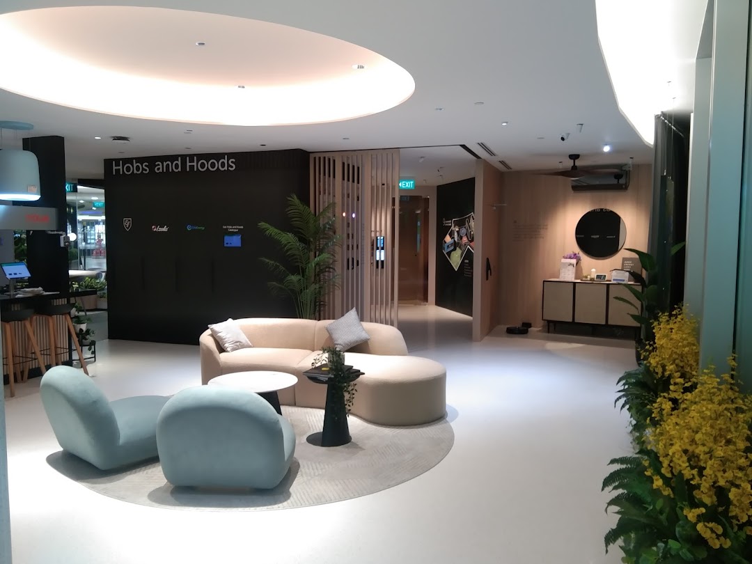 A modern showroom interior featuring comfortable seating, a counter, and a 'Hobs and Hoods' display.