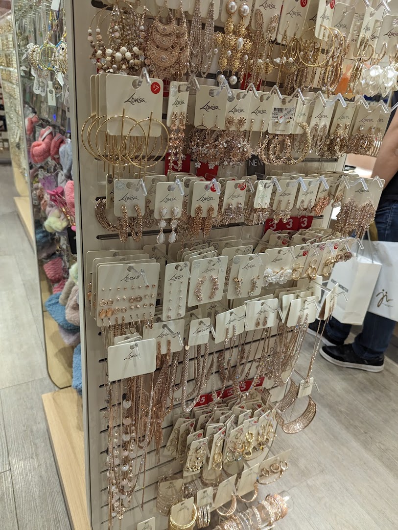 A display stand showcasing a wide variety of gold and rose gold colored fashion jewelry, including earrings and necklaces.