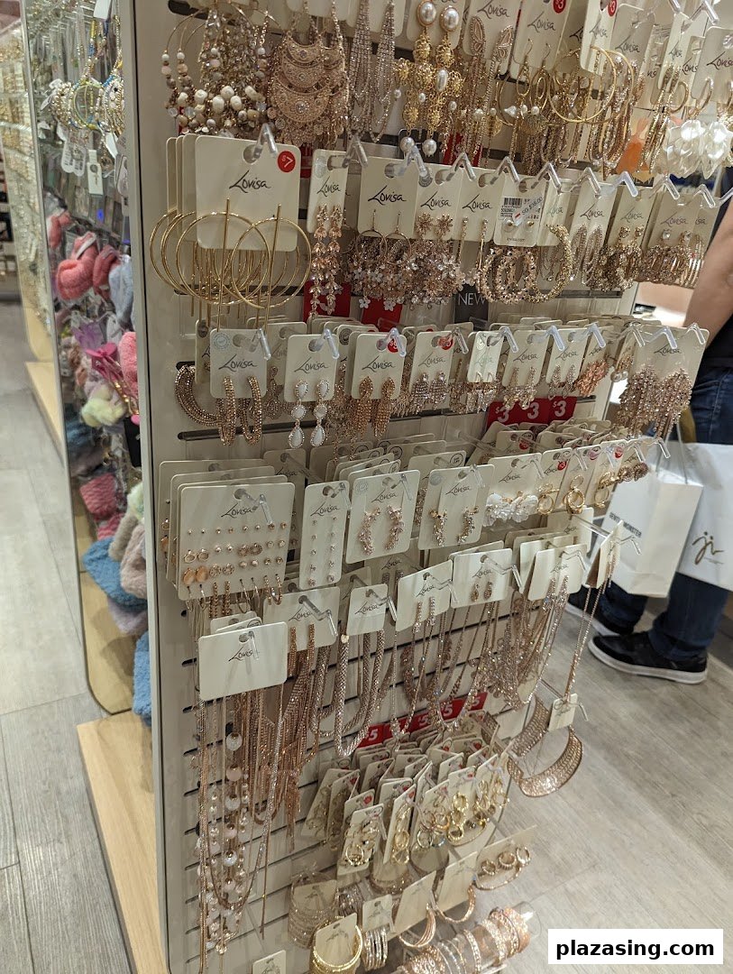 A display stand showcasing a wide variety of gold and rose gold colored fashion jewelry, including earrings and necklaces.