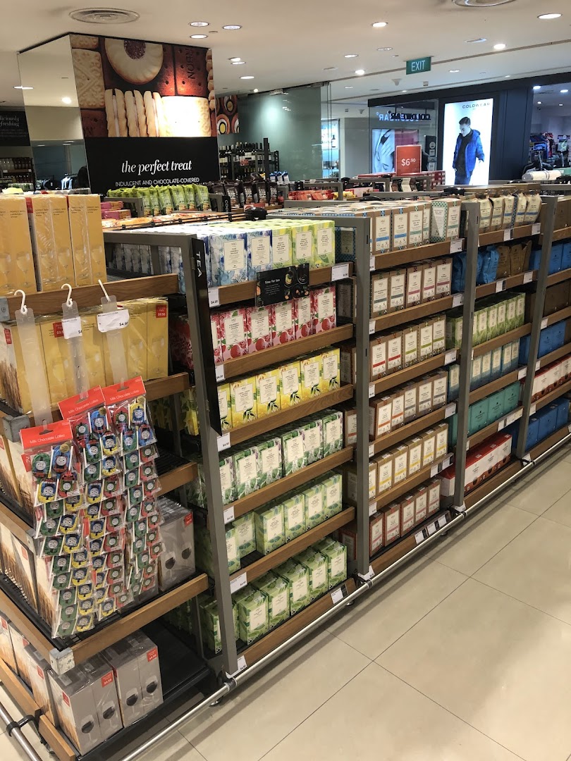 An aisle in Marks & Spencer showcasing a wide variety of teas, biscuits, and other gourmet food items.