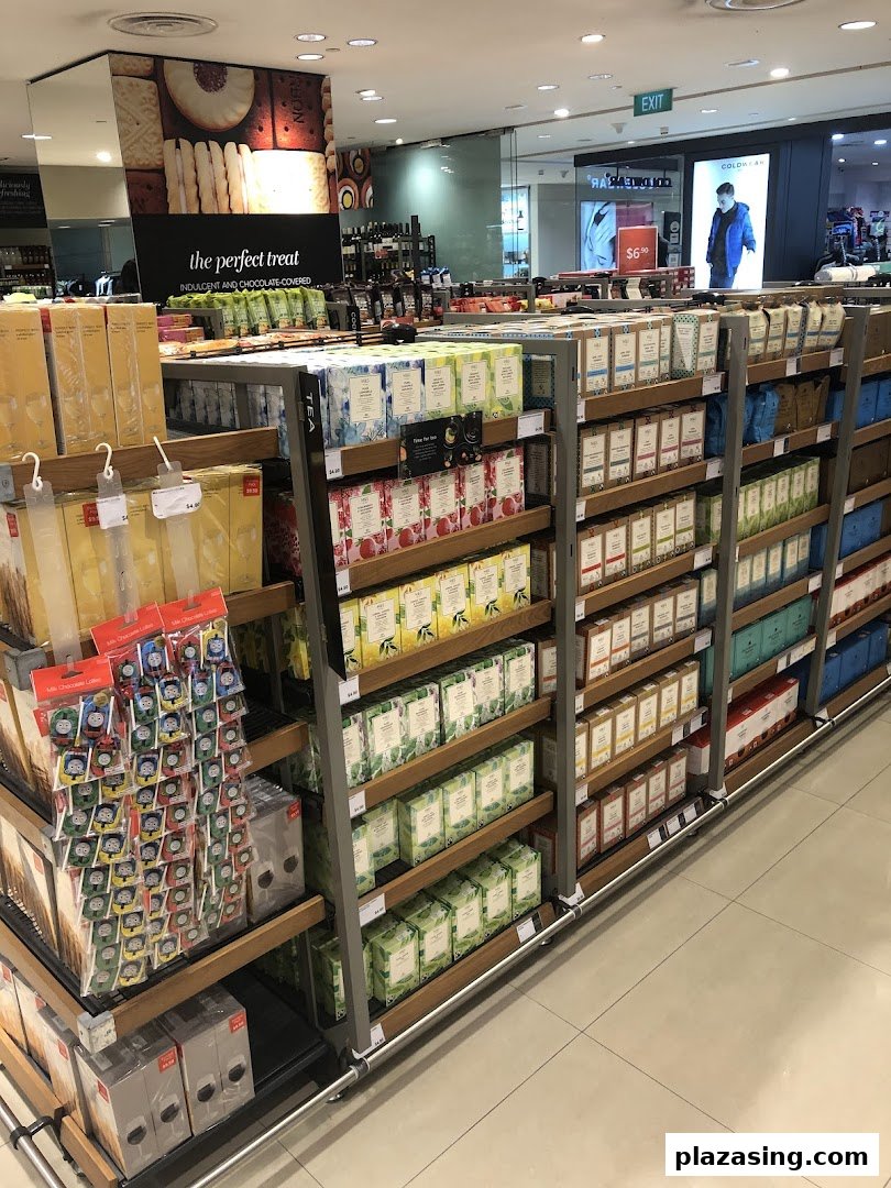 An aisle in Marks & Spencer showcasing a wide variety of teas, biscuits, and other gourmet food items.