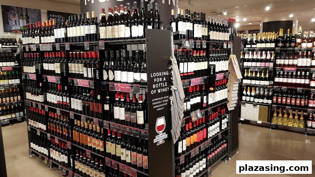 A wide selection of red, white, and sparkling wines displayed on shelves in a Marks & Spencer store.