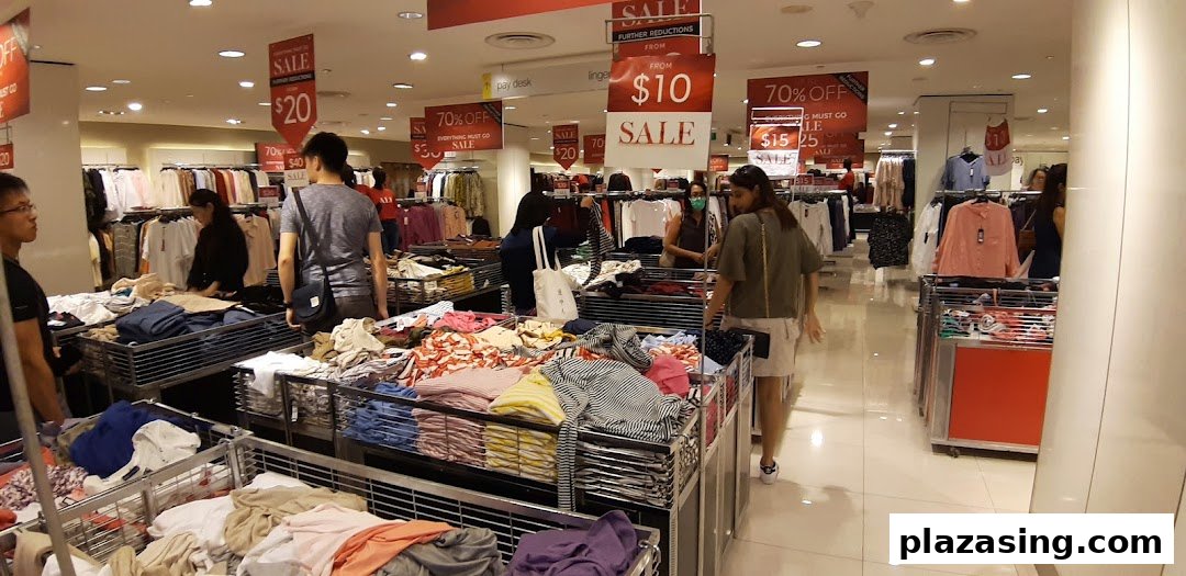 Customers browse clothing racks and sale bins at Marks & Spencer, featuring significant discounts.