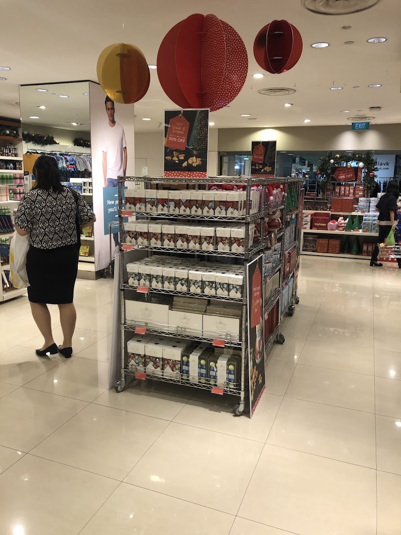 Interior view of Marks & Spencer featuring a festive product display, a shopper, and holiday decorations.