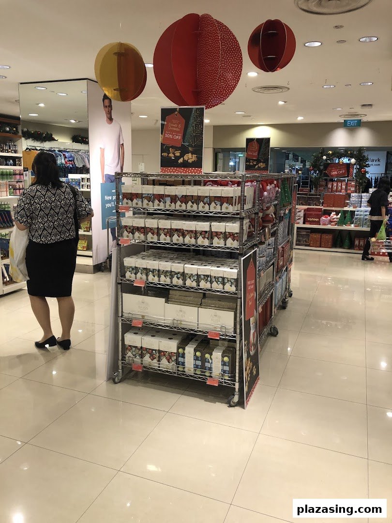 Interior view of Marks & Spencer featuring a festive product display, a shopper, and holiday decorations.