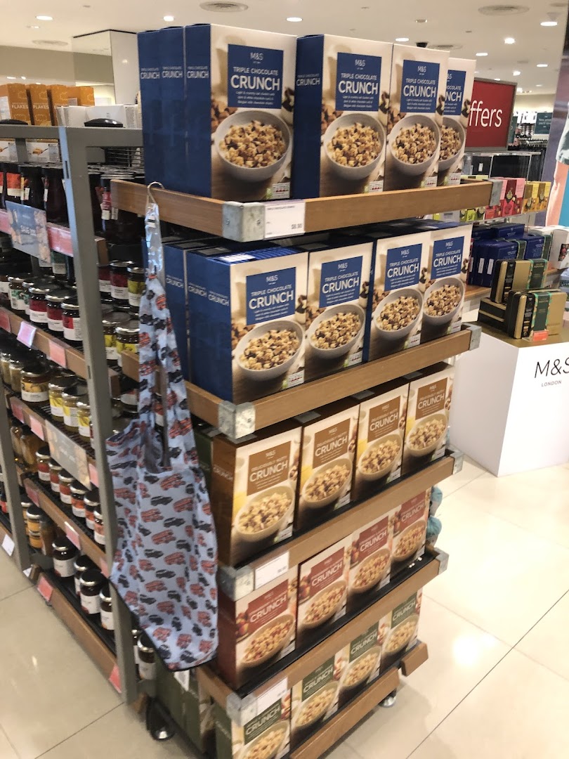 A vibrant display of Marks & Spencer Triple Chocolate Crunch cereals and other M&S food items in a retail store.