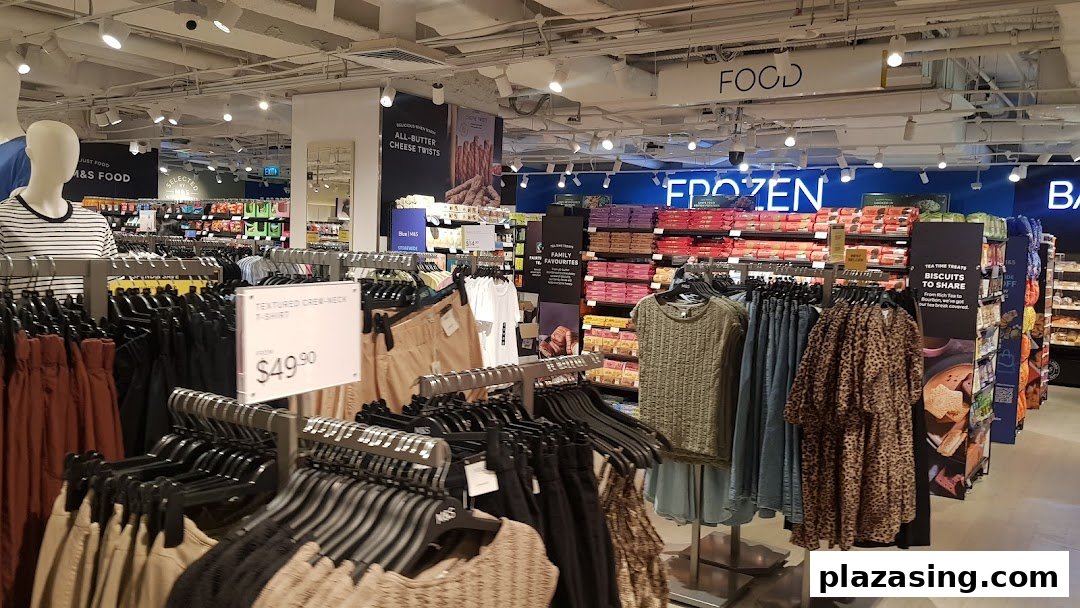 Interior view of Marks & Spencer, showcasing clothing racks and various food sections like frozen and biscuits.