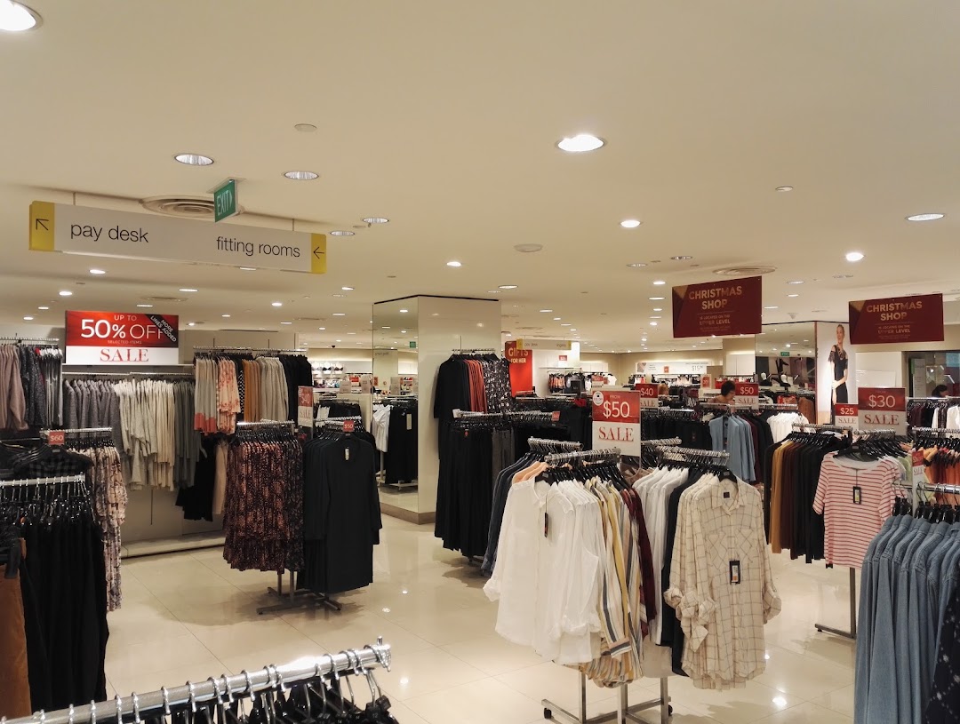Interior view of Marks & Spencer showing clothing racks with sale items and directional signs.