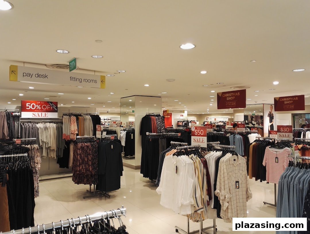 Interior view of Marks & Spencer showing clothing racks with sale items and directional signs.