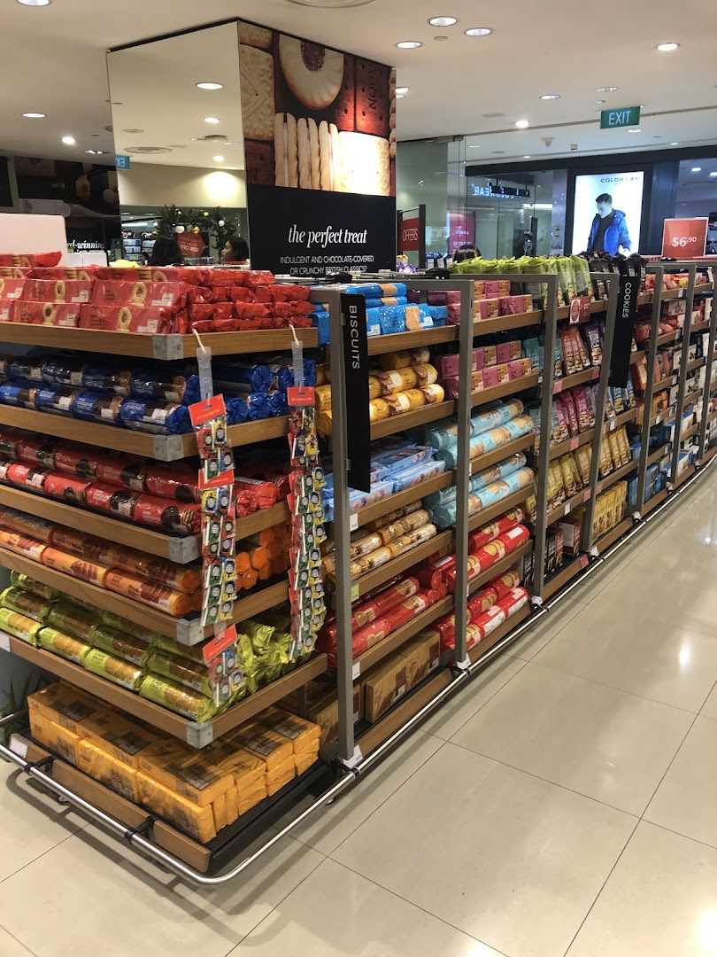 An aisle in Marks & Spencer showcasing a wide selection of biscuits and cookies, including British classics.