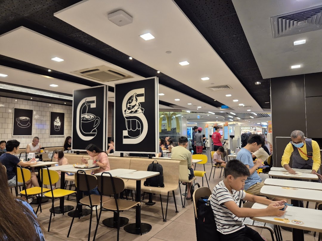 Customers enjoying meals inside the brightly lit McDonald's restaurant at Plaza Singapura.