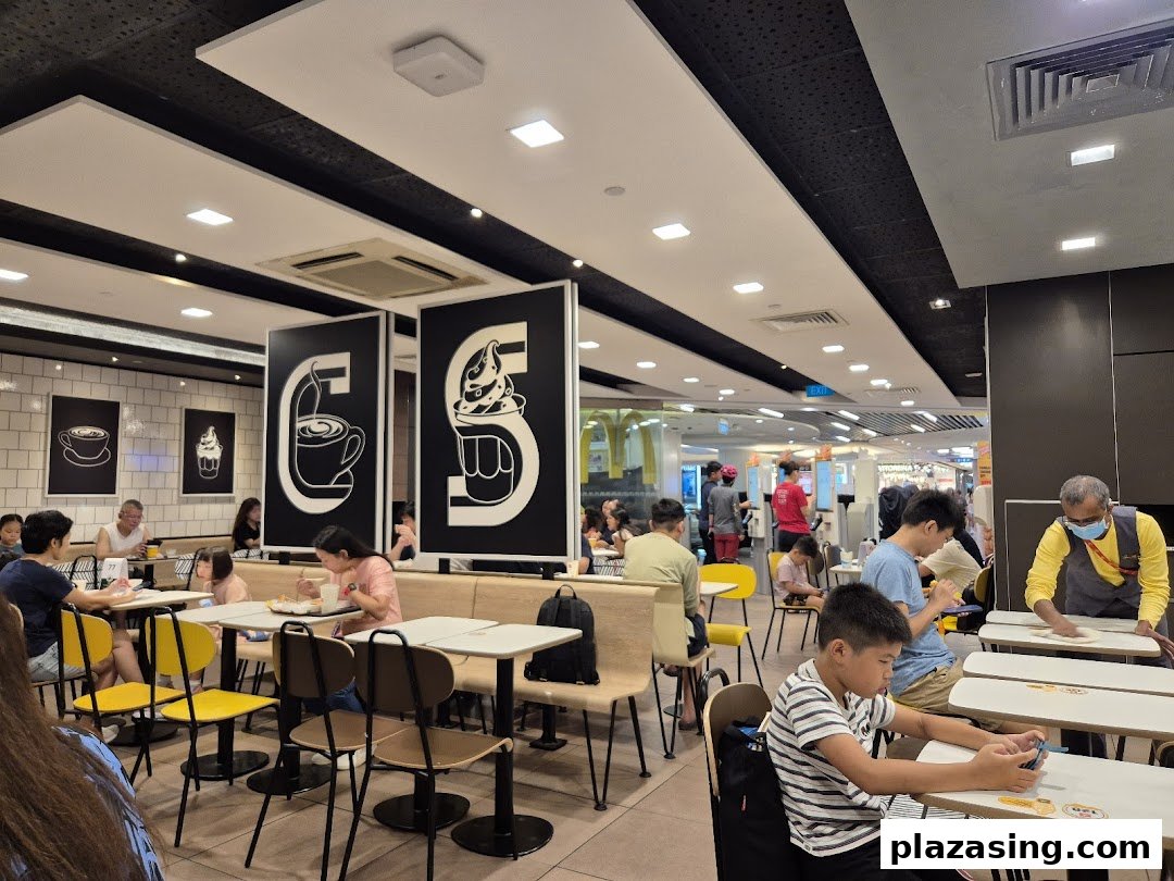 Customers enjoying meals inside the brightly lit McDonald's restaurant at Plaza Singapura.