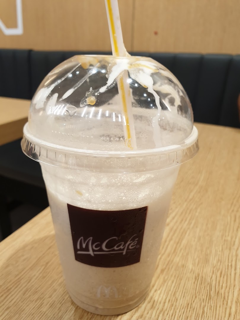 A McCafé drink with a straw on a wooden table inside McDonalds Plaza Singapura.