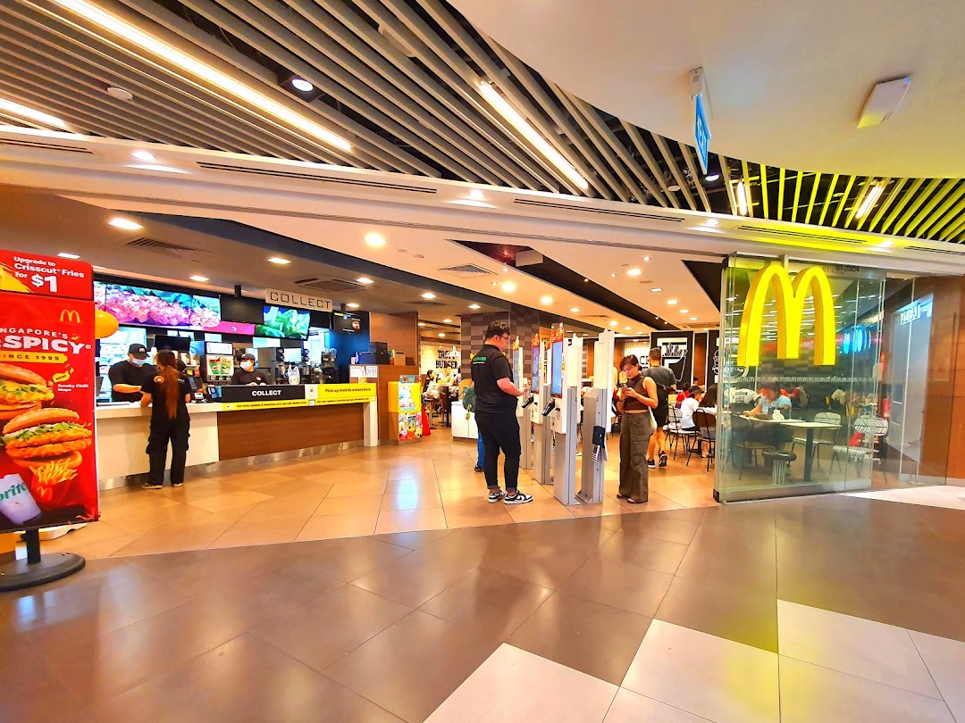 The bustling entrance of McDonald's Plaza Singapura, featuring self-order kiosks and a view of the counter.