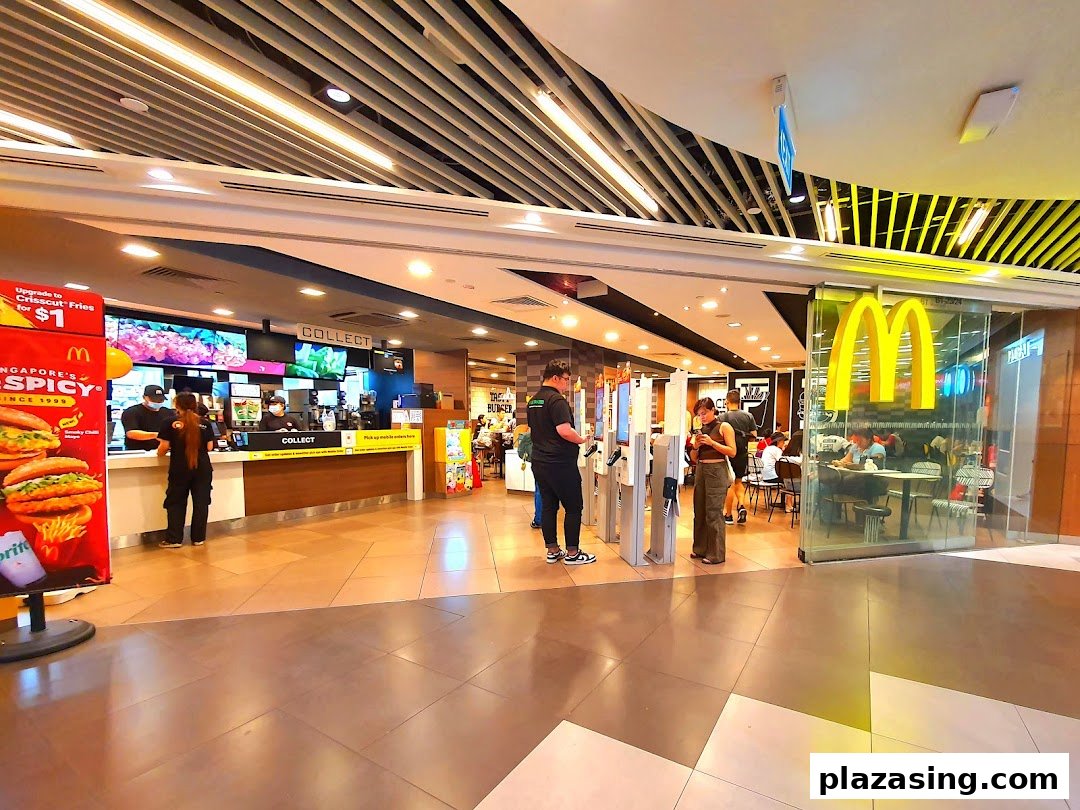 The bustling entrance of McDonald's Plaza Singapura, featuring self-order kiosks and a view of the counter.