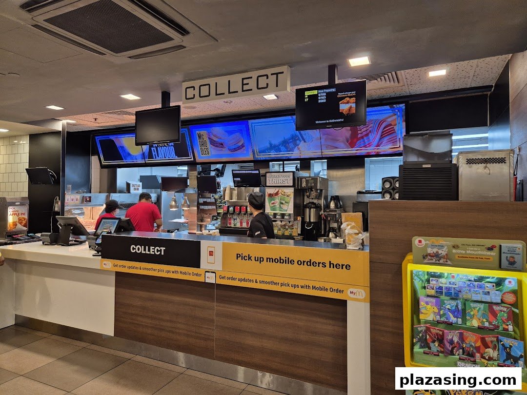 Interior view of McDonald's counter with staff, digital screens, and dedicated order collection points.