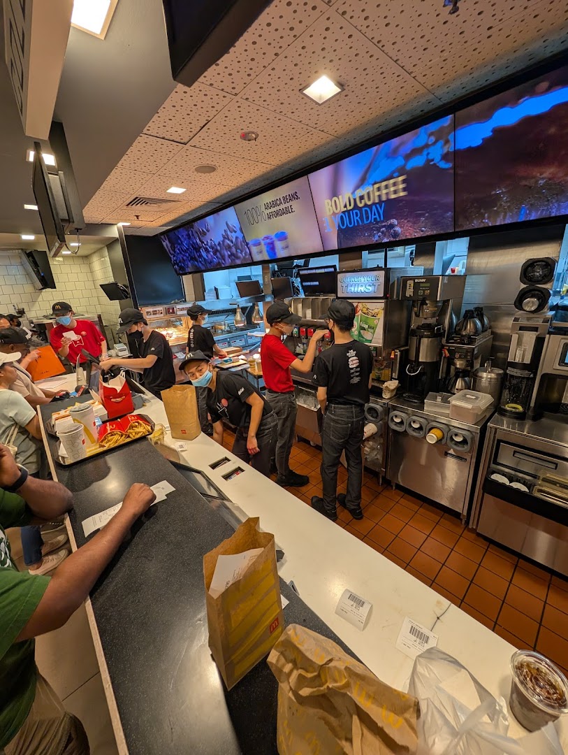 A bustling McDonald's counter with staff preparing orders and customers waiting.