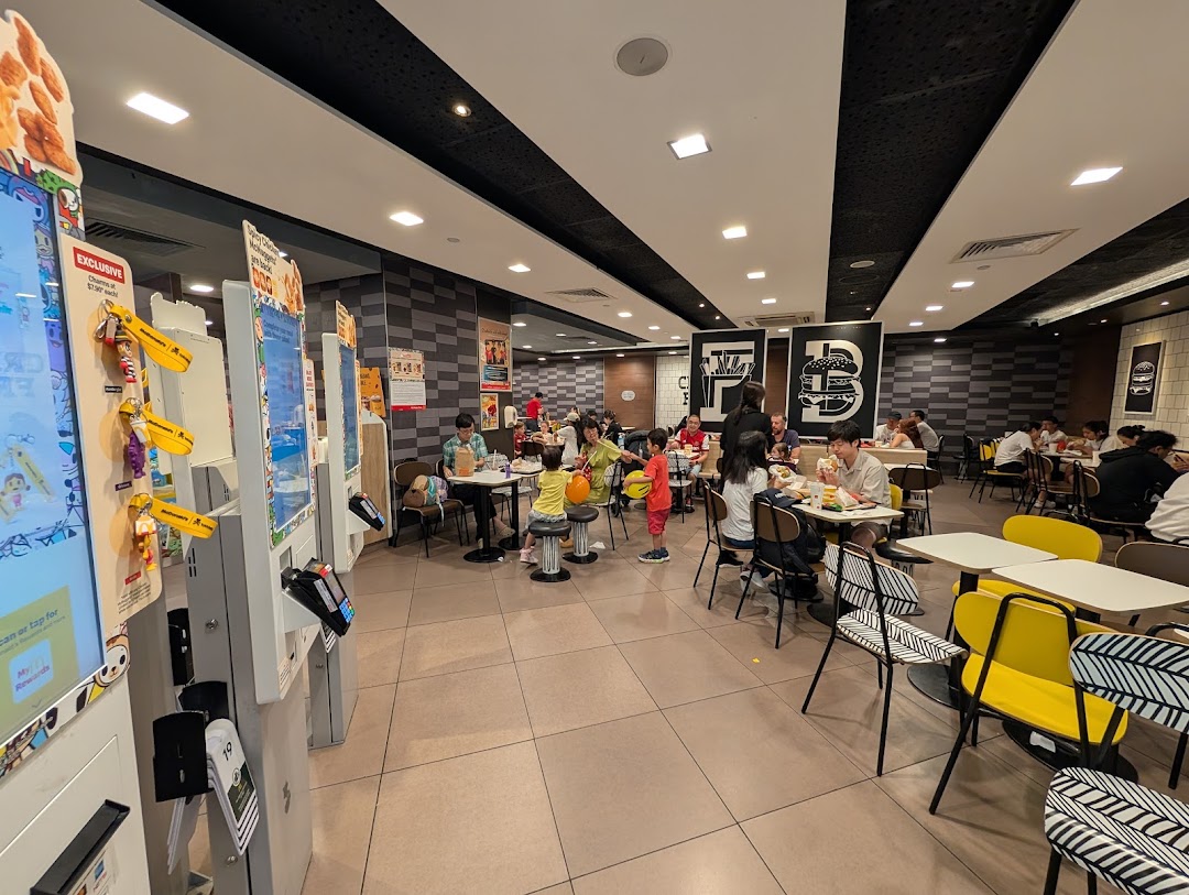 Customers enjoy meals in the spacious, modern dining area of McDonald's, featuring self-order kiosks.