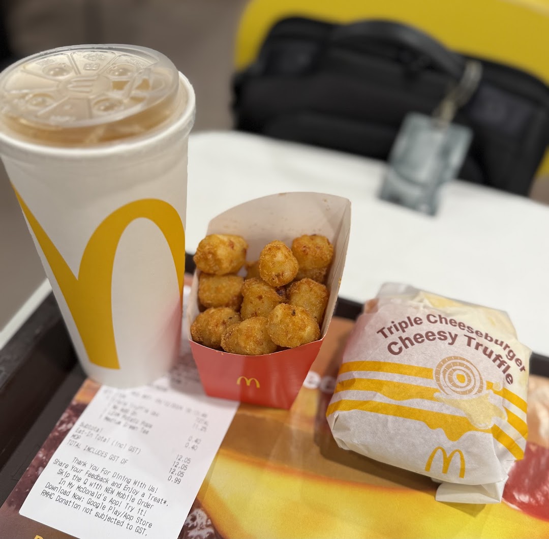 A McDonald's meal featuring a Triple Cheeseburger Cheesy Truffle, tater tots, and a drink.