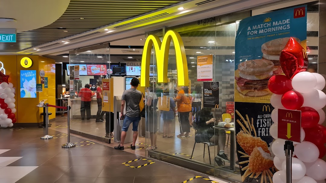 The vibrant yellow McDonald's entrance with prominent golden arches, promotional posters, and queue management.