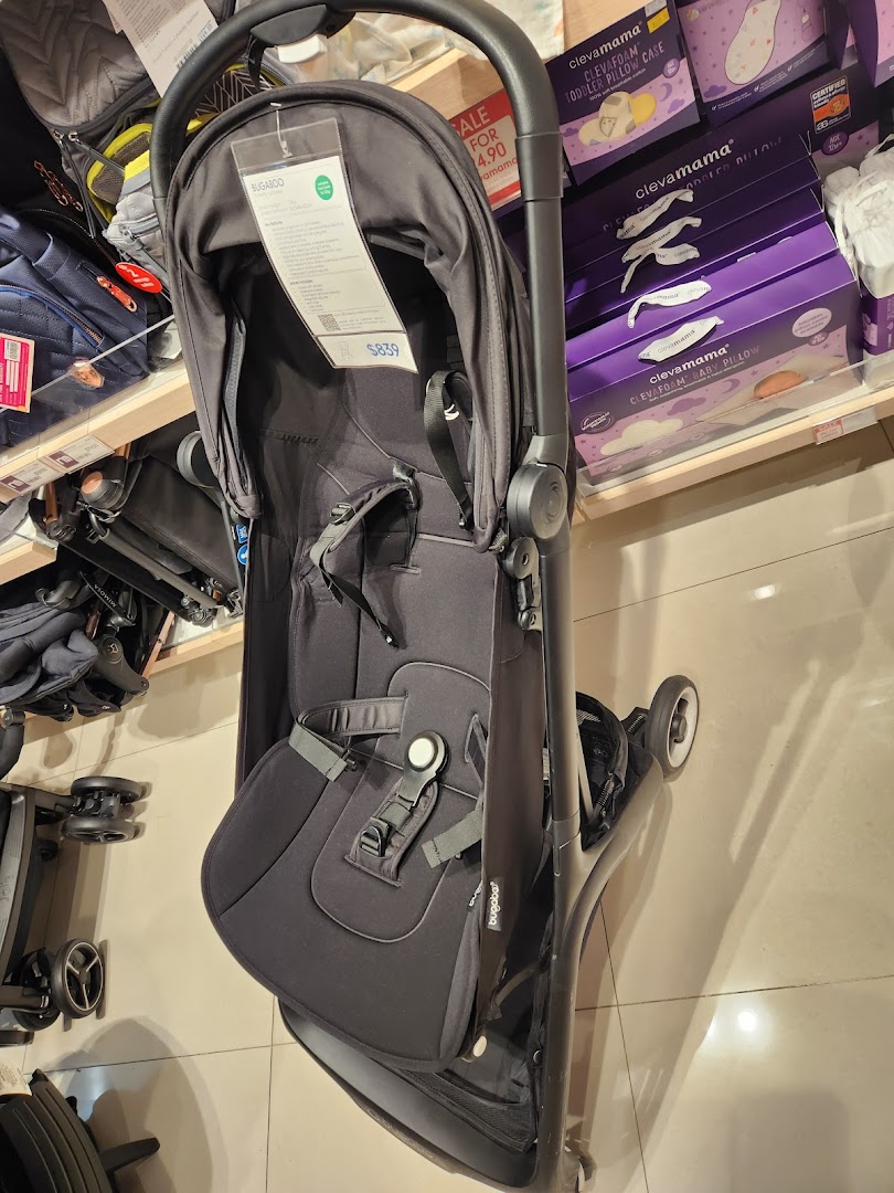A black Bugaboo stroller displayed in a Mothercare store, surrounded by other baby products.