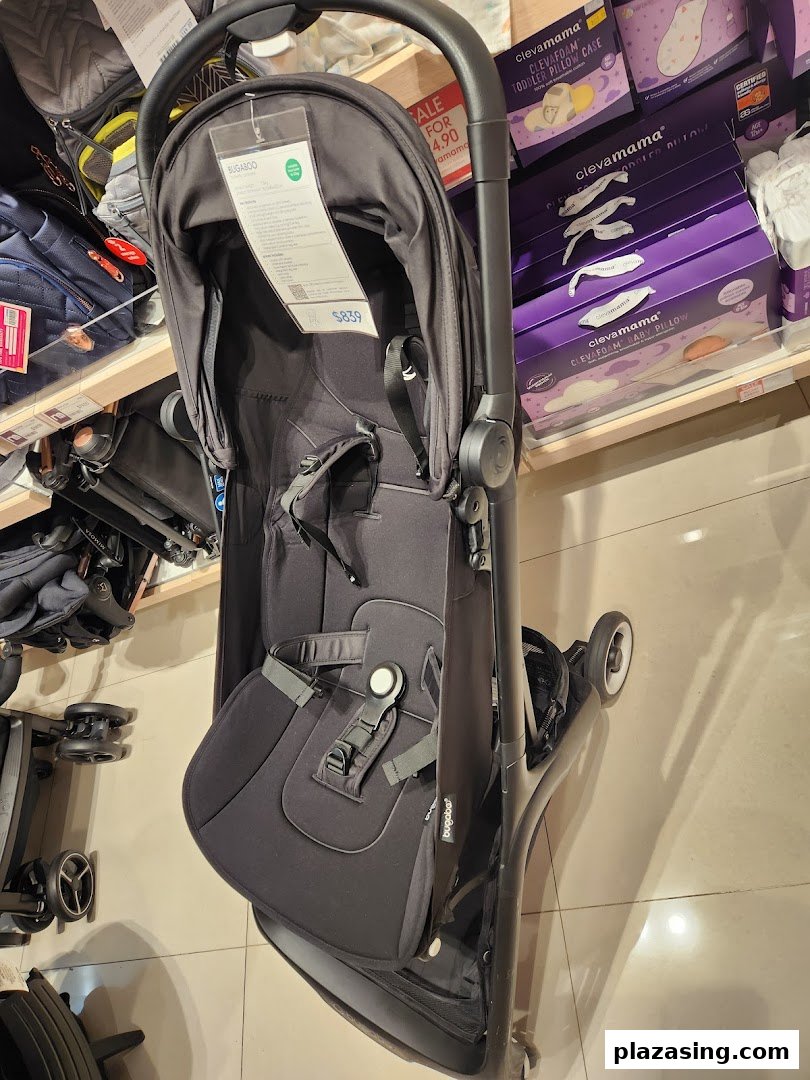 A black Bugaboo stroller displayed in a Mothercare store, surrounded by other baby products.