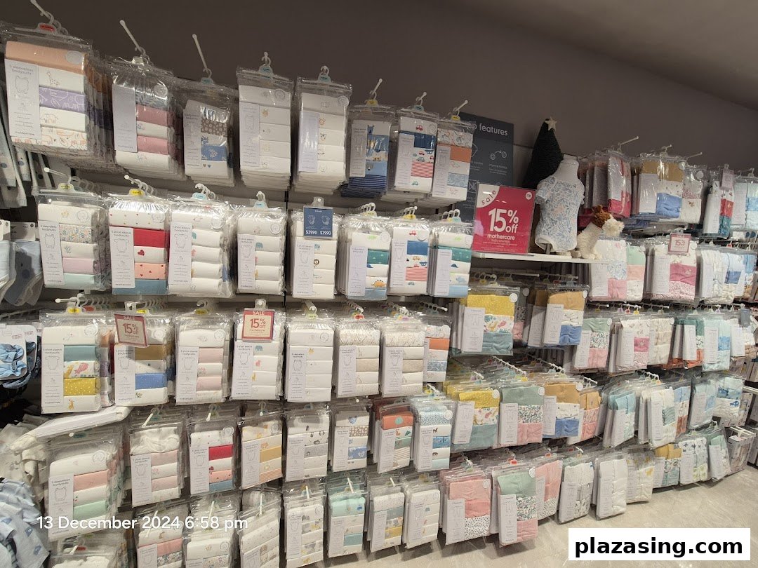 A wide selection of packaged baby clothing, including bodysuits, displayed on racks in a Mothercare store.