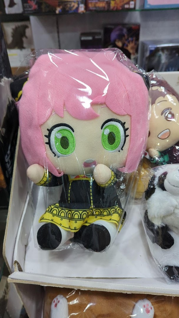 Close-up of a pink-haired anime character plush toy, likely Anya Forger, displayed in a retail setting.