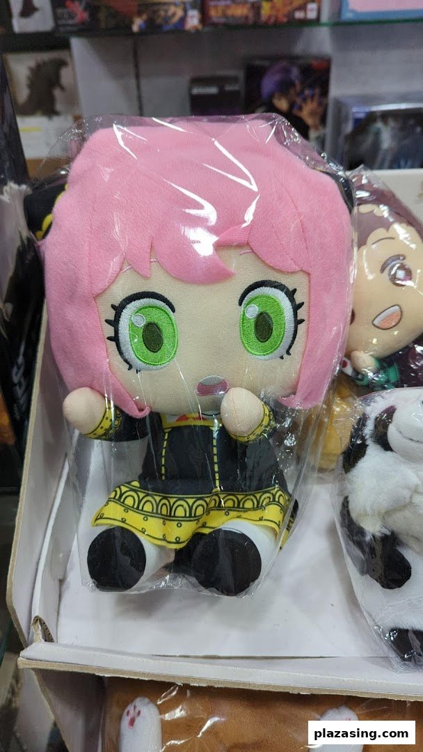Close-up of a pink-haired anime character plush toy, likely Anya Forger, displayed in a retail setting.