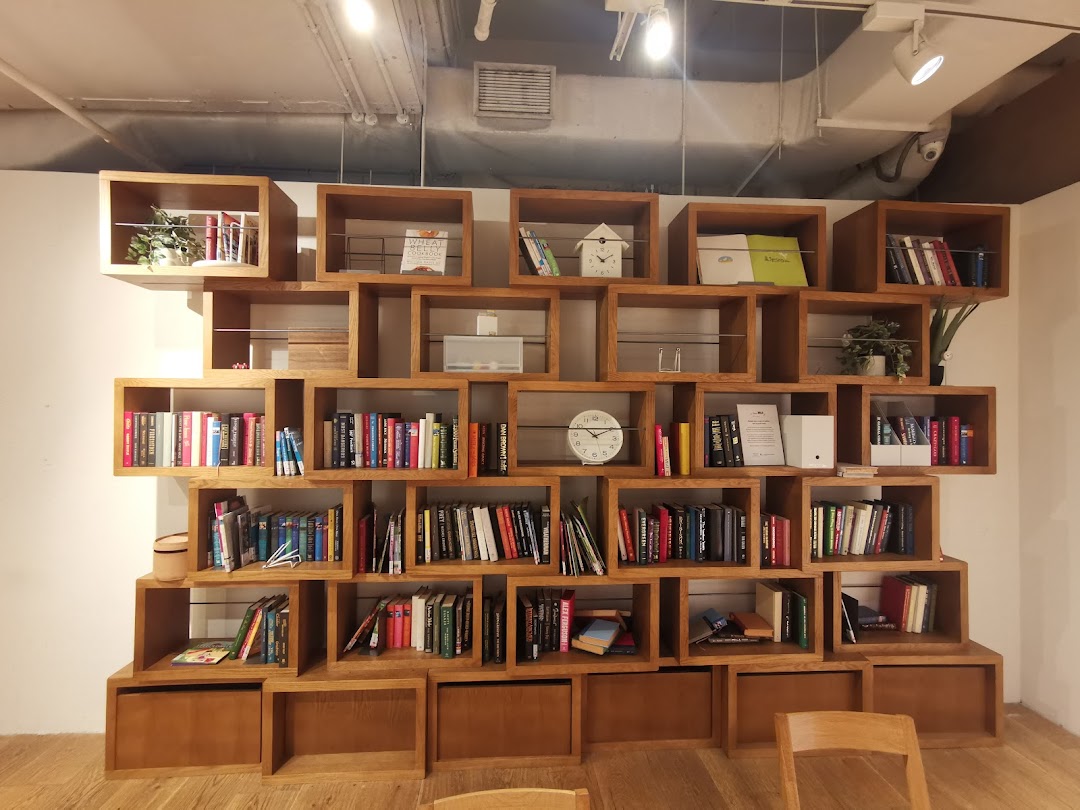 A large, modern wooden bookshelf filled with books and decorative items, showcasing MUJI's minimalist aesthetic.