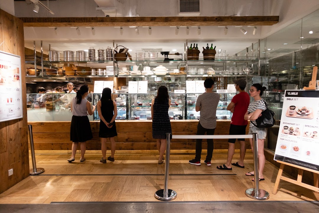 Customers queueing at the deli counter inside MUJI, showcasing food displays and kitchenware.