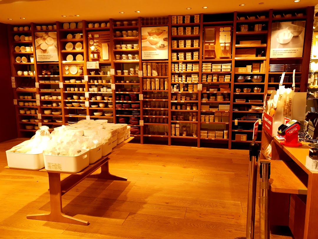 Interior view of MUJI showcasing extensive wooden shelves filled with household goods and kitchenware.