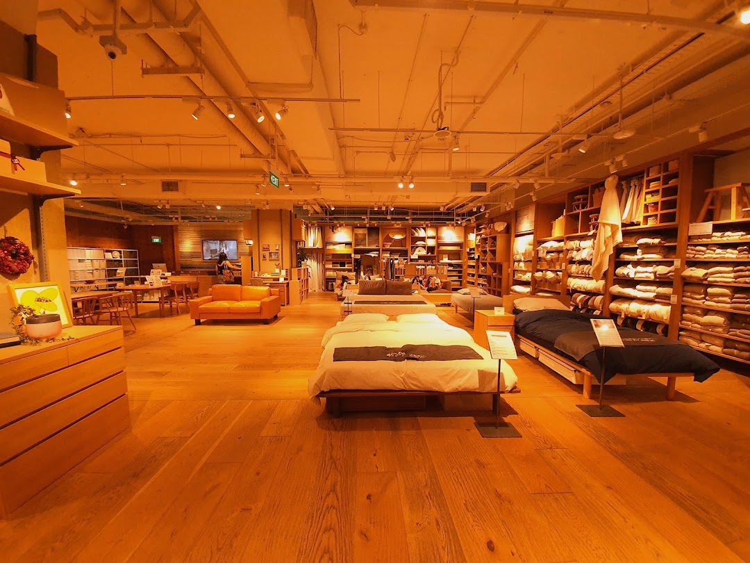 Spacious MUJI store interior showcasing furniture, bedding, and home essentials in a warm, minimalist setting.