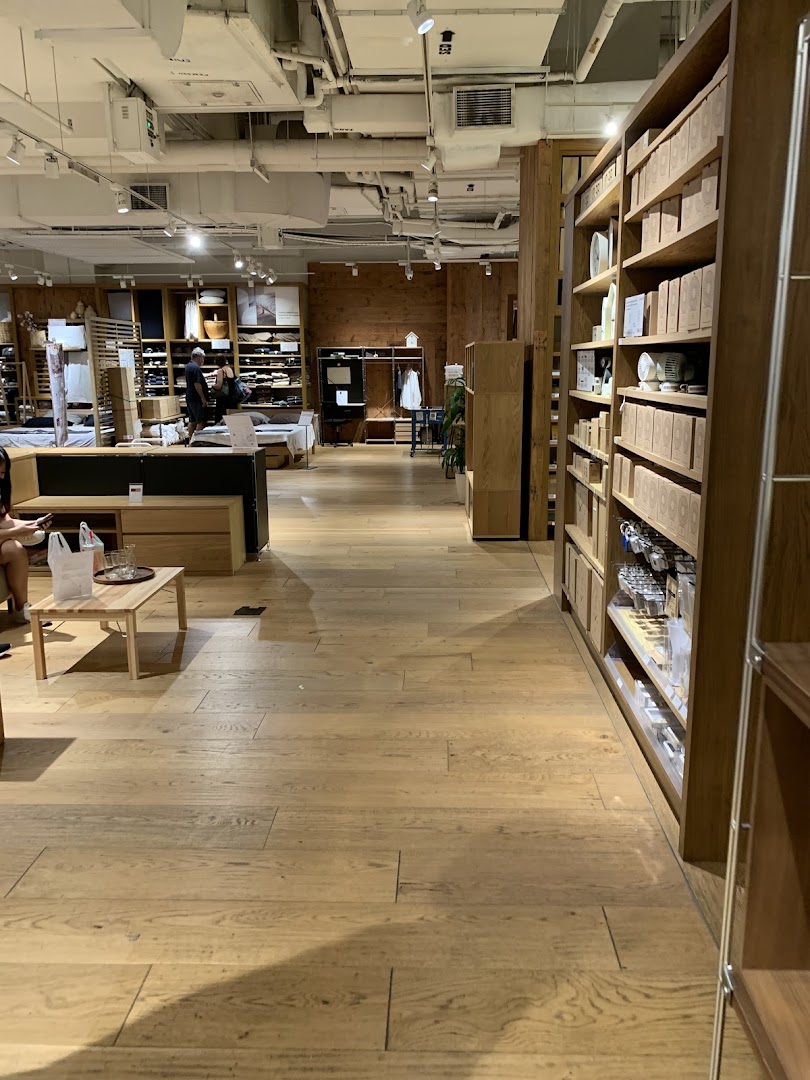 Interior view of MUJI Plaza Singapura, showcasing wooden shelves filled with products and a minimalist design.