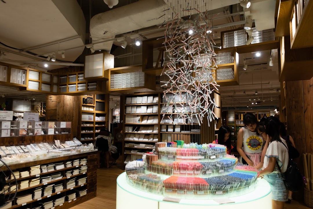 Customers browse stationery and home goods in the minimalist interior of MUJI Plaza Singapura.